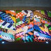 Vibrant surfboards displayed against a colorful geometric mural backdrop.