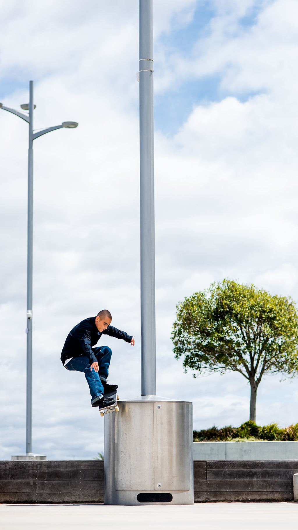 Skateboarder performing a trick on a metal structure under a bright sky.