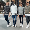 Men showcasing versatile hooded sweatshirts styled with jeans and sneakers on a city street.