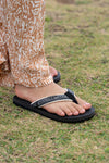 FoamLife Yogi black flip flops worn outdoors on grass.
