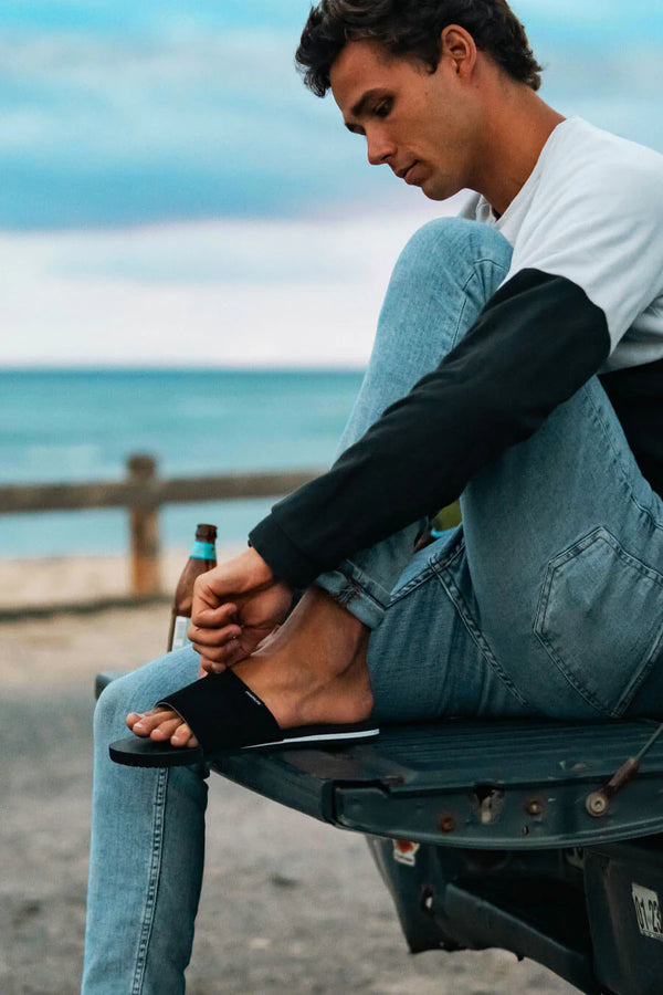 Man wearing FoamLife Tarlan Slide black sliders by the beach.
