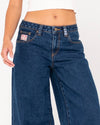 Close-up of front details on Rusty Low Rise Super Wide Leg Jean with logo patch.