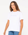 Rusty Jill Standard Fit Tee in white with minimalist front logo, styled casually.