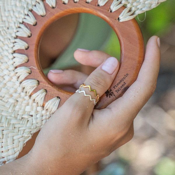 Silver and gold ripple wave rings on hand holding a woven accessory.