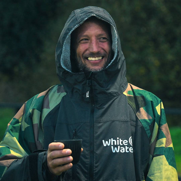 White Water Adults Hard Shell Robe in camo, hooded man holding a cup outdoors.