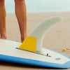 Close-up of a longboard fin on a surfboard at the beach.