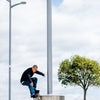 Skateboarder performing a trick on a metal structure under a bright sky.