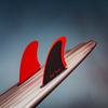 Dead Kooks surfboard with vibrant red Deflow fins against a moody backdrop.