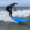 Person riding a wave on a blue surfboard during a surf therapy session.