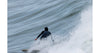 Surfer in a sleek 1mm wetsuit riding a powerful ocean wave.