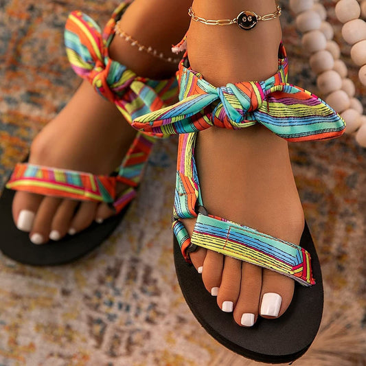 Colorful women's sandals with vibrant striped fabric straps and ankle tie design.