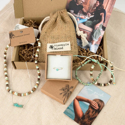 Boho-style jewelry set with necklaces, bracelets, and a ring by Pineapple Island, displayed in eco-friendly packaging.