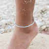 Beach-inspired Avalon clay beaded anklet on a sandy foot.