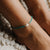 Turquoise beaded anklet with a white shell centerpiece, worn on ankle.