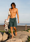 Model wearing Vissla Pismo Painter Eco Short in moss green near a beach.