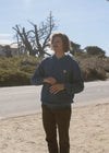 Model wearing Vissla Solid Sets Eco Po Hoodie in SEA blue outdoors.