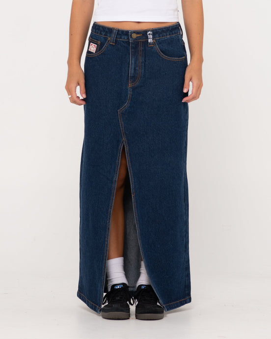 Rusty Celeste low-rise denim maxi skirt with front slit, styled casually.