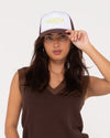 Model wearing Rusty Bless You Trucker Cap with casual outfit.