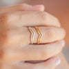 Close-up of silver and gold Pineapple Island Breaking Wave Wishbone Rings stacked on fingers.