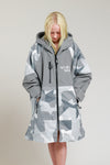 Child wearing White Water Kids Hard Shell Robe in Arctic Camo/Grey with hands in pockets.