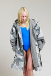 Child in swimwear wearing White Water Kids Hard Shell Robe in Arctic Camo/Grey.