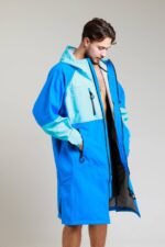Man showcasing the interior lining of the White Water cobalt blue soft shell robe with hands in pockets.